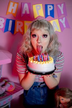 Blonde woman having fun at a birthday party with a vibrant cake and playful decorations.