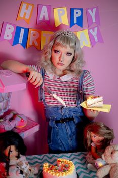 Young woman cutting cake at a lively birthday party with vibrant decor.