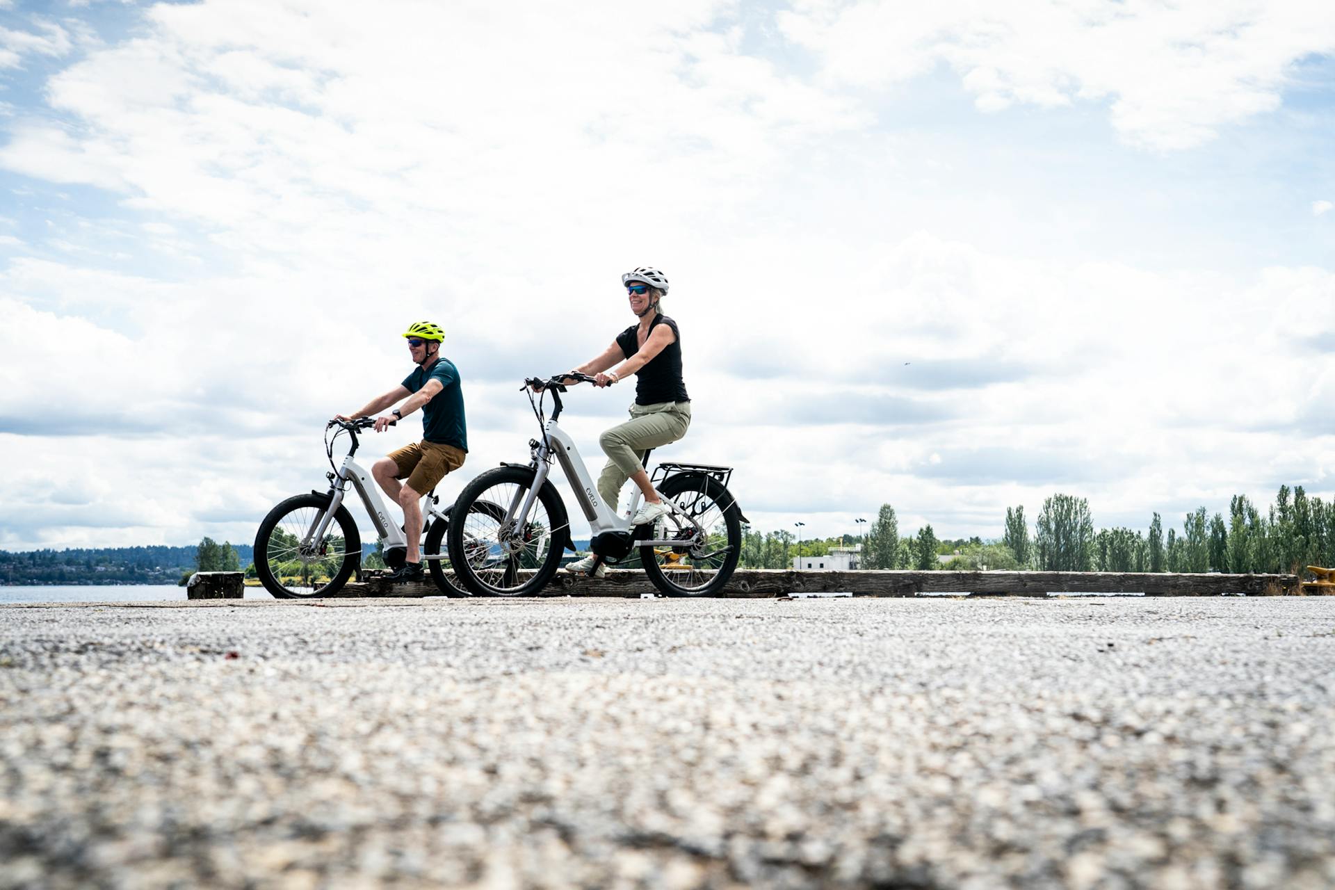 A Couple Wearing Helmets Riding Electric Bikes