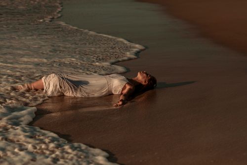 Free A serene moment captured as a woman lies on the sandy shore of Florianópolis beach. Stock Photo
