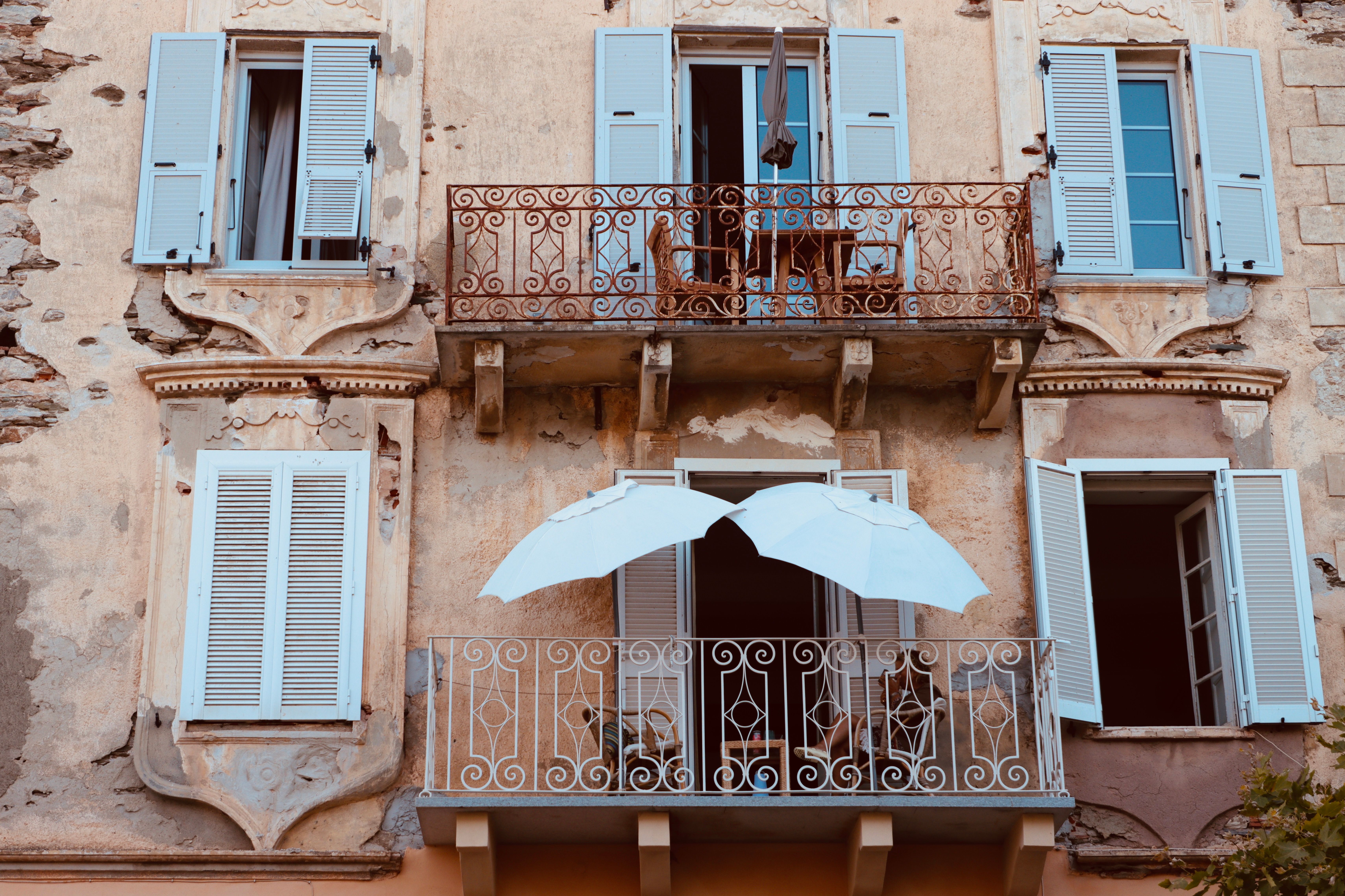 Rustic building facade with elegant balconies and white shutters, capturing timeless urban charm.