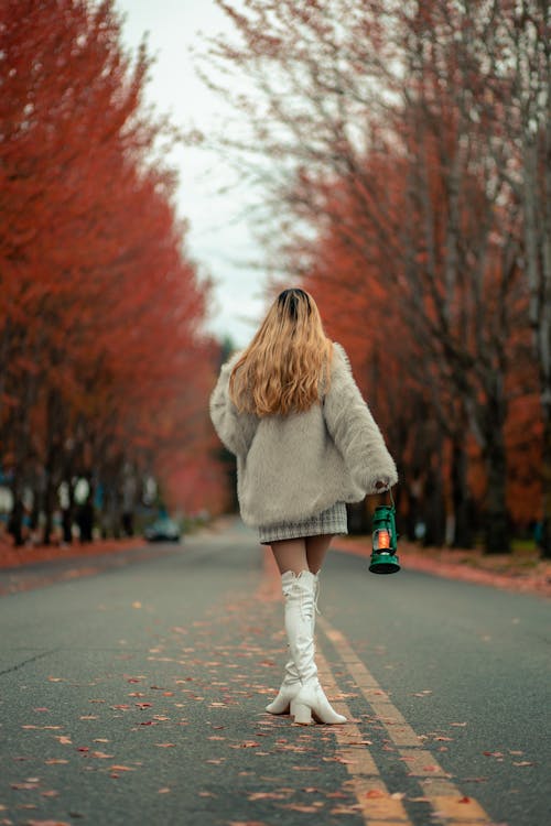 Woman in Fur Coat Standing in the Middle of the Road Holding a Lantern