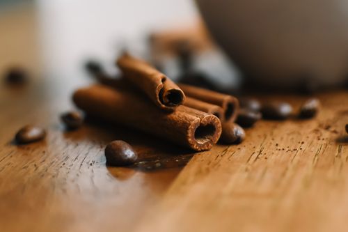 Free Aromatic cinnamon sticks with scattered coffee beans on a wooden surface. Stock Photo