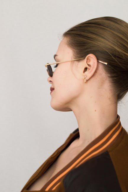 Profile portrait of a woman wearing sunglasses against a neutral background, captured in a studio.