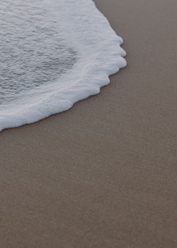 Close-up of a gentle ocean wave upon the sandy shore in Australia.