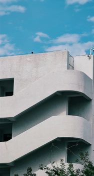 A minimalistic urban building featuring curved concrete staircases under a clear blue sky.