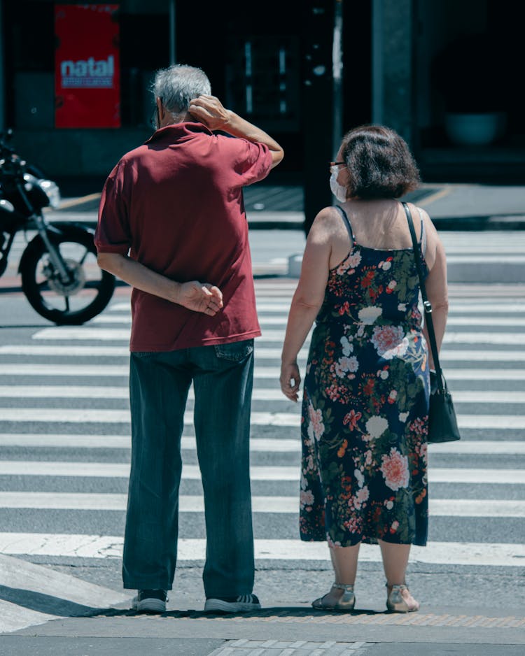 An Elderly Couple Standing Near A Crosswalk