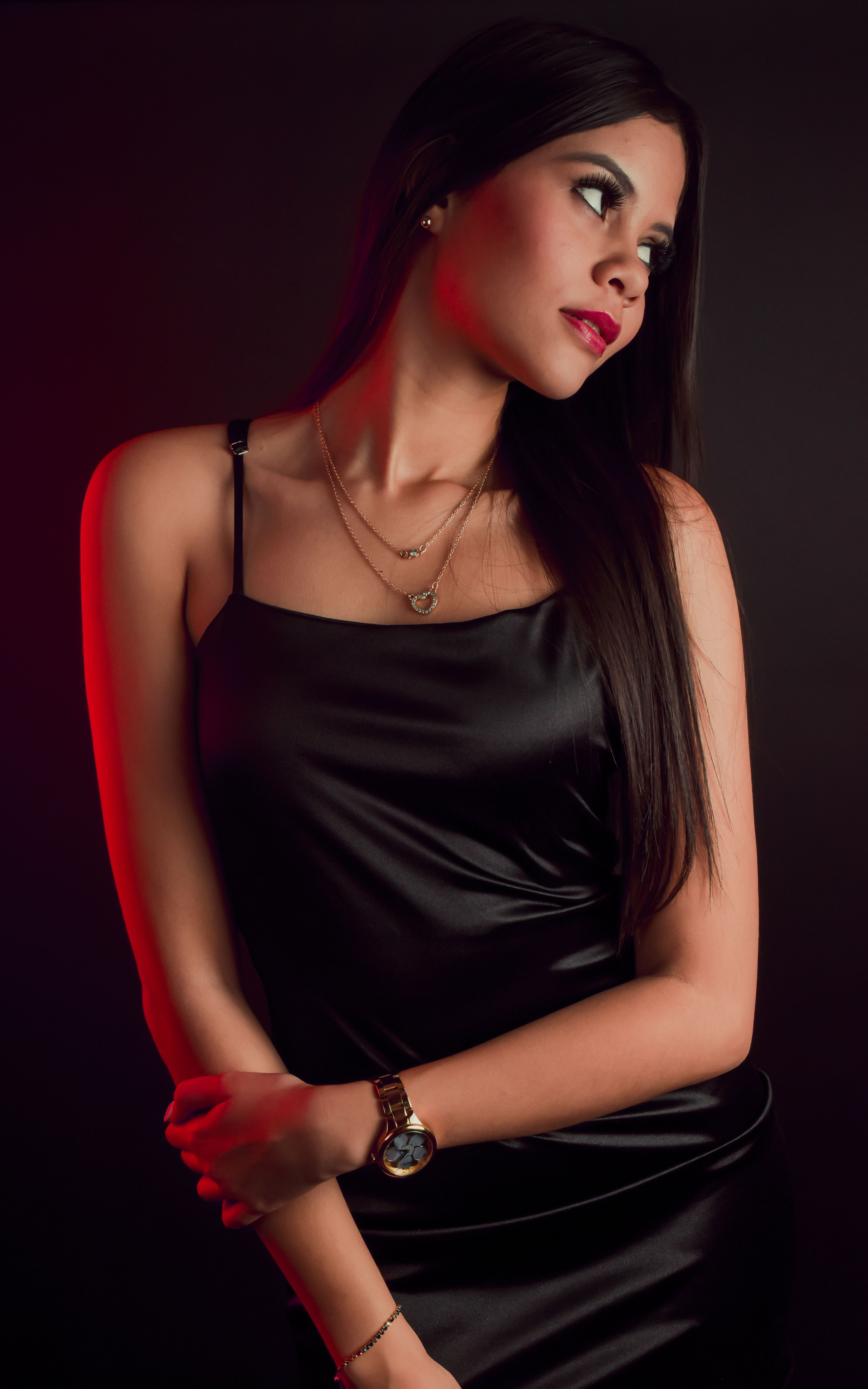Woman in black slip dress with gold accessories