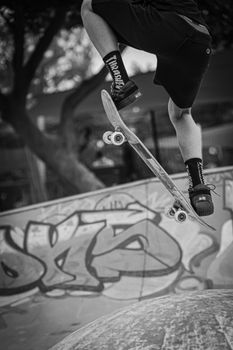 Monochrome image of a skateboarder mid-air performing a trick in an urban skatepark.. monochrome, image, skateboarder