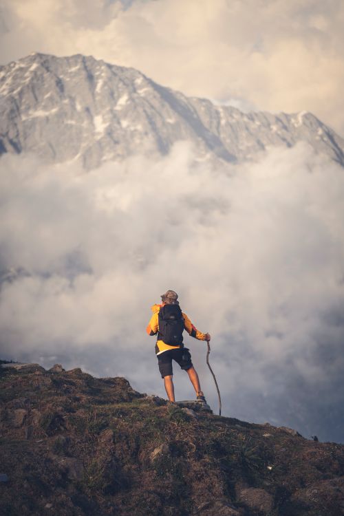 Free Backpacker enjoying a hike in the mountains with stunning cloud and peak views. Stock Photo