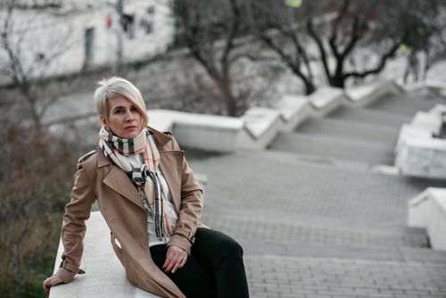 Free Blonde woman in a trench coat posing on an outdoor staircase, showcasing urban fashion. Stock Photo