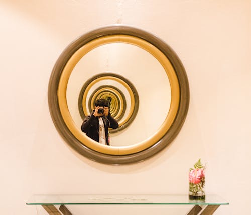 Человек размышляет о круглом коричневом зеркале в деревянной раме