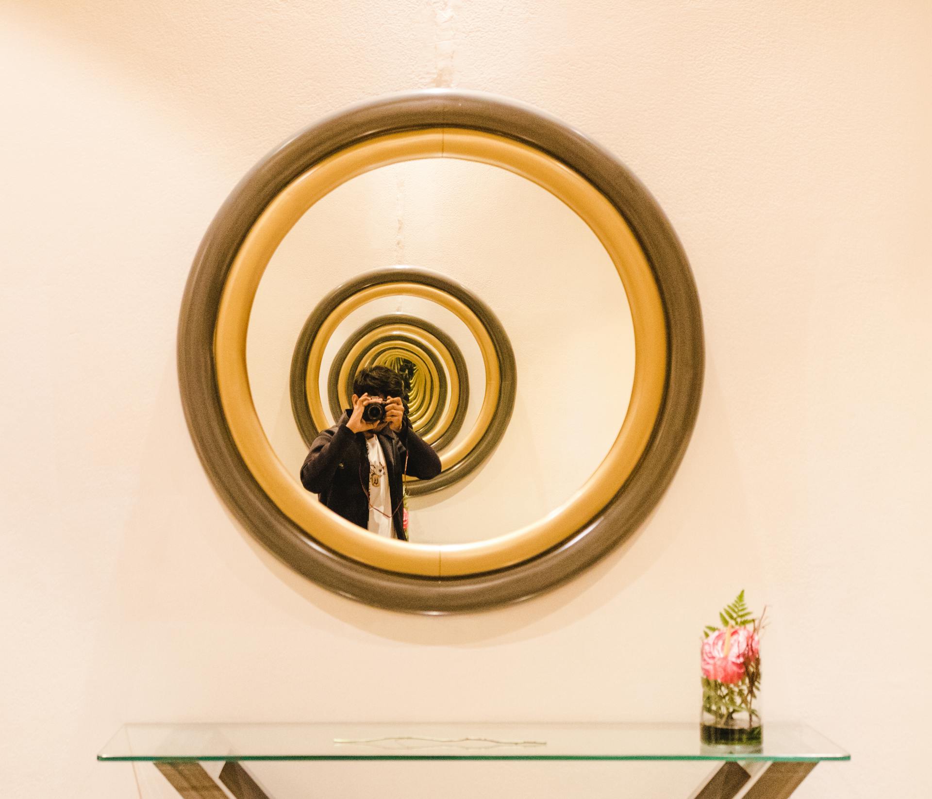 A photographer taking a picture through multiple mirrors creating a visual infinity effect indoors.