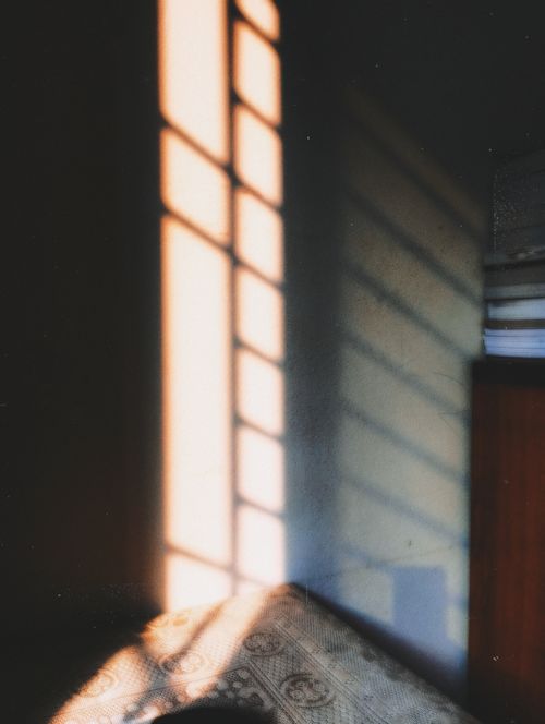 Free Warm sunlight creating shadows on a wall in a cozy room setting. Stock Photo