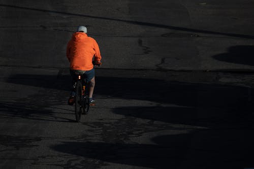 Man in an Orange Jacket Riding a Bike 