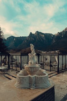 Beautiful terrace featuring a detailed statue with stunning mountain backdrop under cloudy sky.