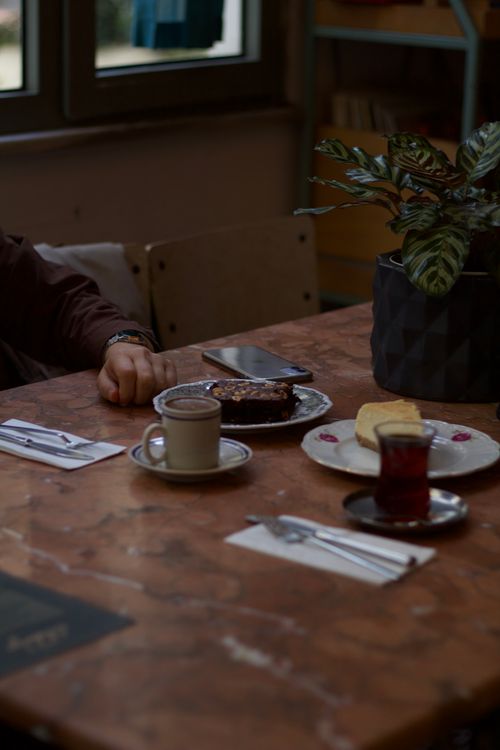 Free A cafe table set with various hot beverages, pastries, and a smartphone for a relaxing break. Stock Photo