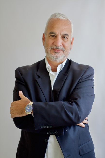 Portrait of a confident senior businessman with arms crossed in a studio setting.