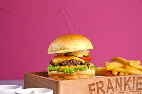 Free A burger and fries on a wooden tray with a sign that says frankie's Stock Photo