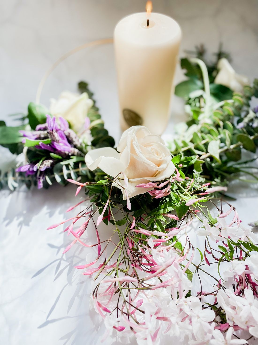 Brennende Kerze und weiße Rosen auf einem Tisch