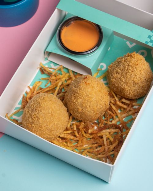 Free Three crispy croquettes with sauce on shredded fries, captured in a vibrant setting. Stock Photo