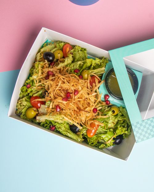 Free Colorful salad with lettuce, olives, tomatoes, and dressing in a takeout box. Stock Photo