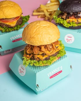 Tempting burgers with crispy onions and cheese in colorful packaging, perfect for fast food lovers.