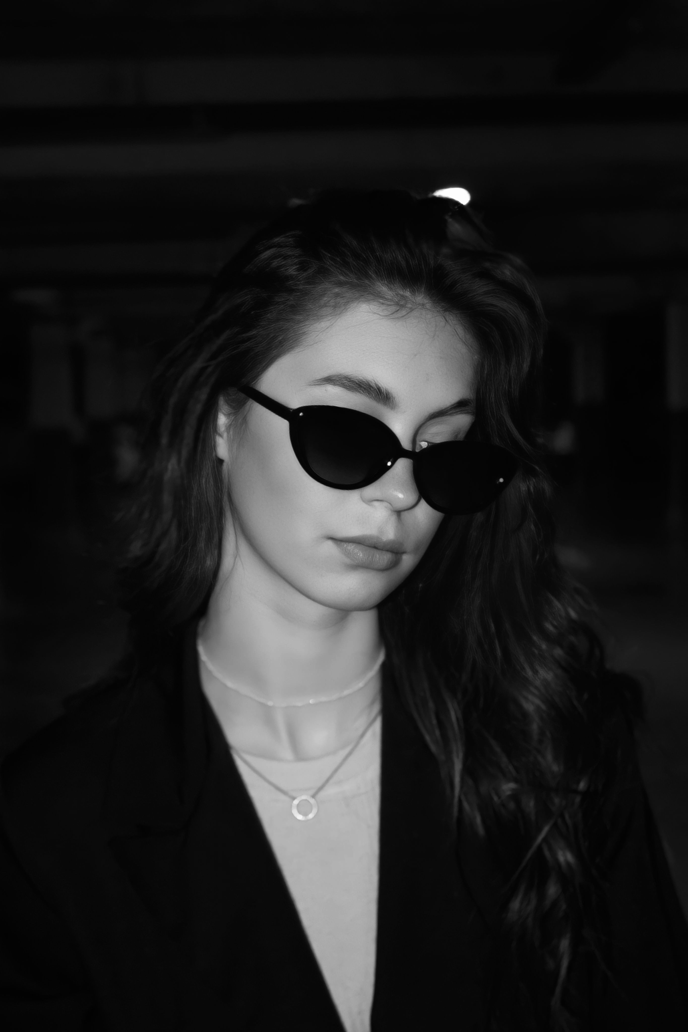 Black and white portrait of a woman wearing sunglasses in a minimalist style.