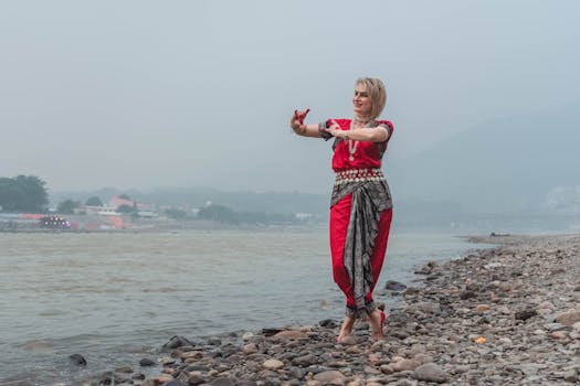 A woman performs Odissi dance along the riverbank in Rishikesh, India, embodying grace and tradition.