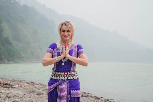 Odissi dancer poses gracefully in traditional attire by a serene riverside.