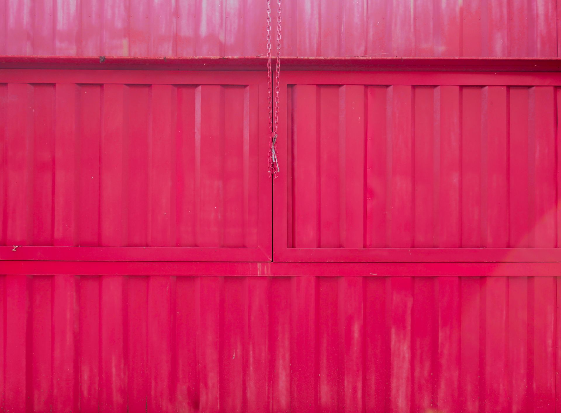 A vivid red industrial garage door with a hanging chain. Perfect for construction or design themes.