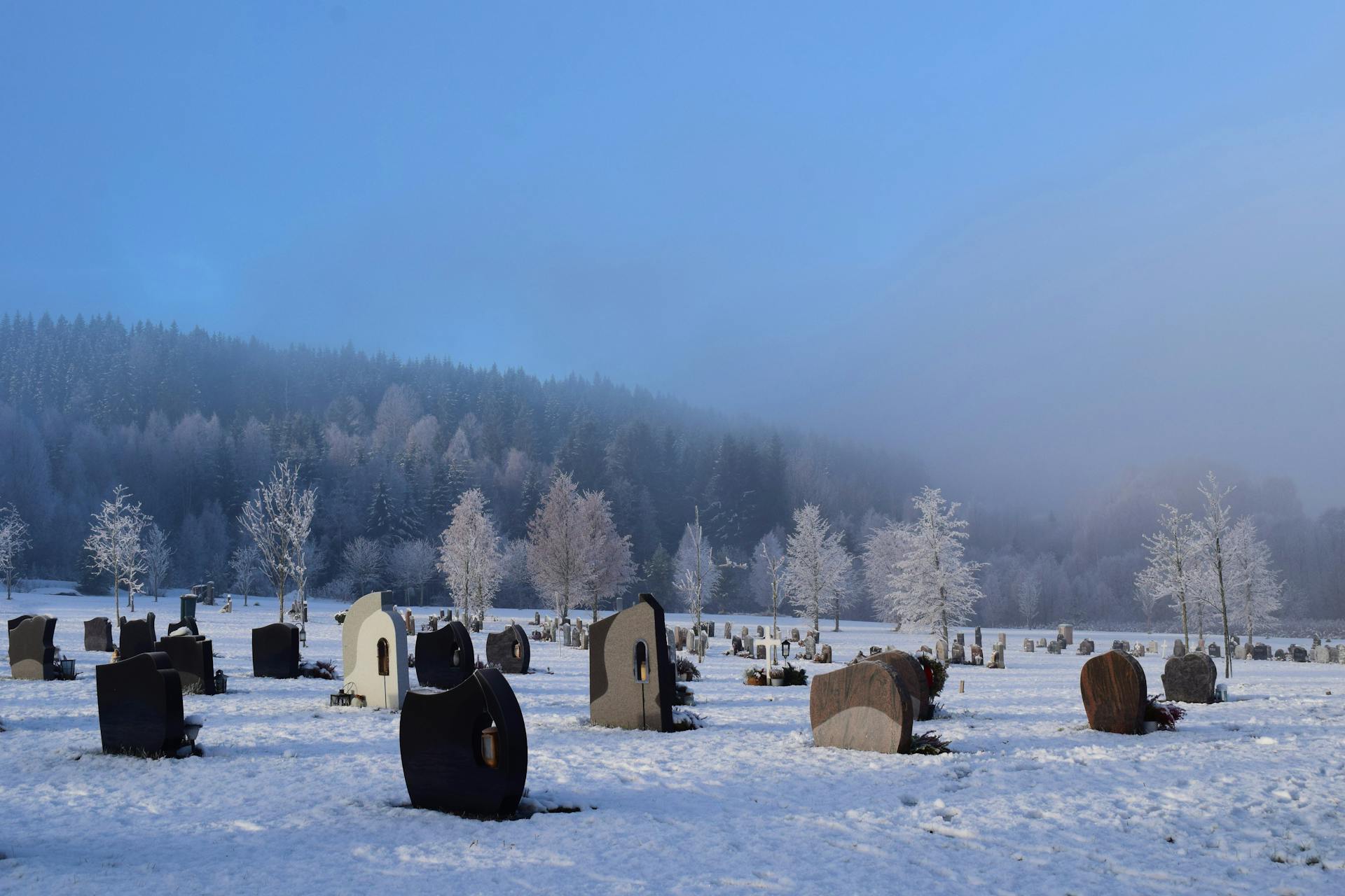 Snow-covered cemetery in Kongsvinger, Norge with frosty trees and gravestones.