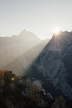 Sunset illuminating Soča Valley in Slovenia, casting dramatic shadows across rugged alpine mountains.