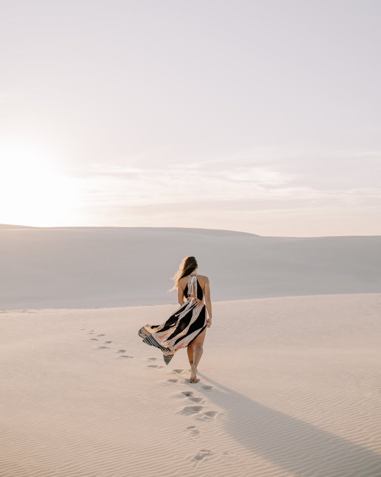 Woman In Dress Walking In Sand Dunes