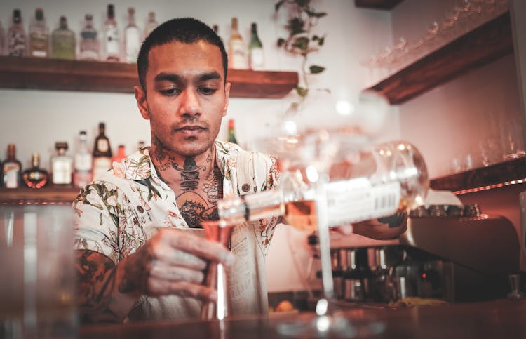 A Bartender Pouring Liquor Into A Shot Glass