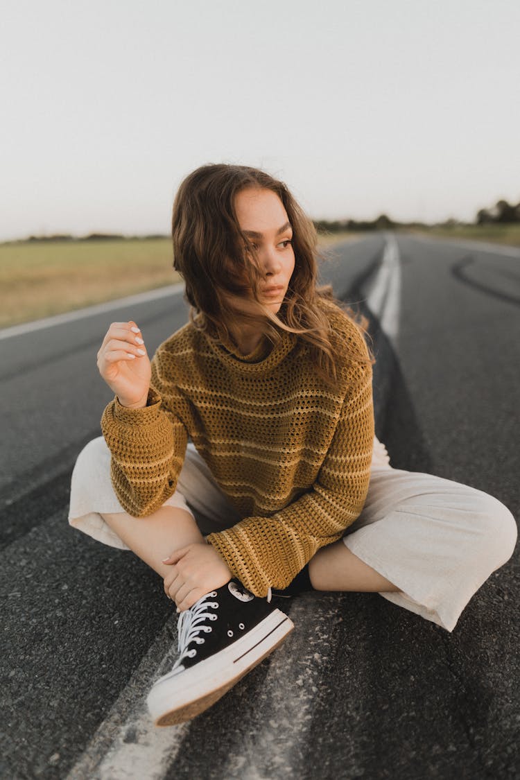 Woman In Knitted Sweater Sitting On Road