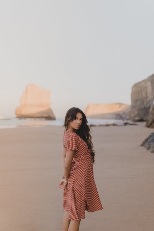 Woman Wearing a Dress Standing on a Beach 