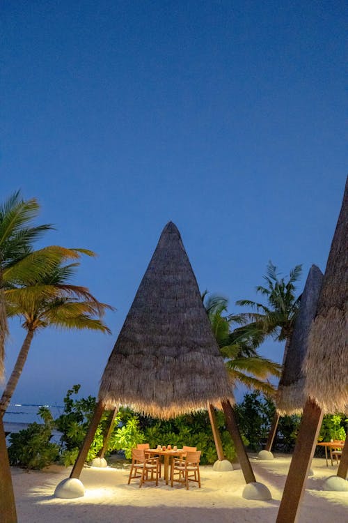 A beach with thatched roof and tables