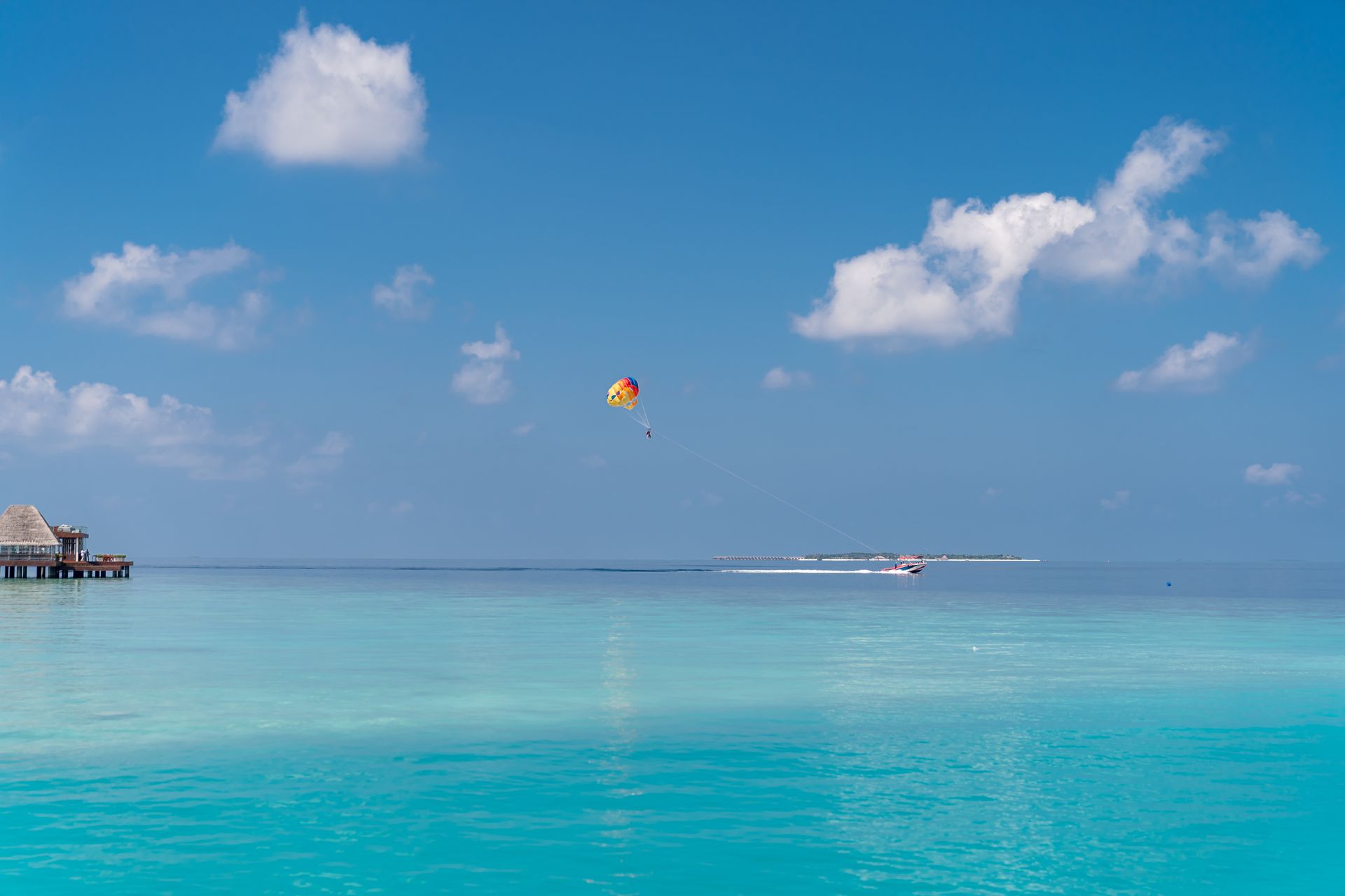 Idyllic tropical scene featuring parasailing over turquoise waters under a clear blue sky.