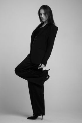 Model in a dark tailored suit against a pale studio wall, photo by Vitaly Gorbachev on Pexels