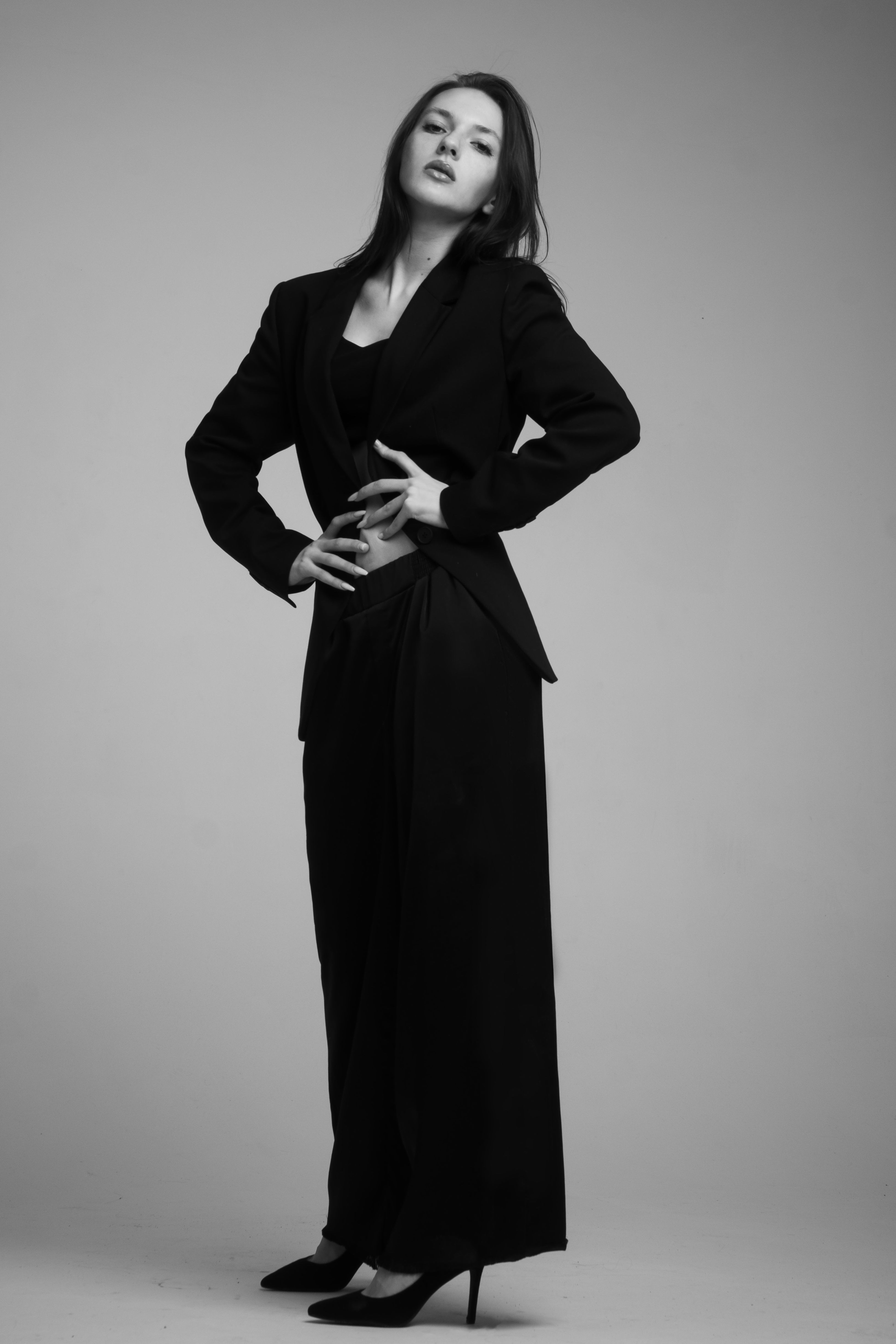 Striking black and white portrait of a woman in formal attire posing confidently in a studio.