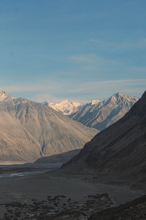 Free Admire snow-capped mountains against a serene dusk sky over a tranquil valley. Stock Photo