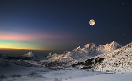 Aurora Borealis and a full moon on sky in Lofoten islands, Northern norway