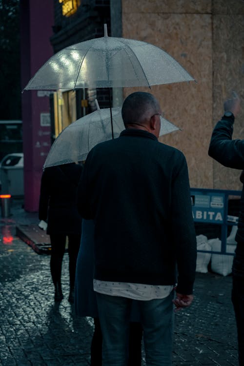 People with Umbrellas on Night Street