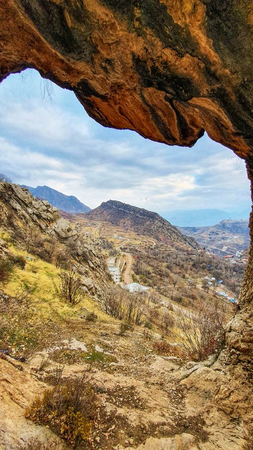 Free Stunning landscape view framed by a natural rock archway, revealing a rugged canyon scenery. Stock Photo