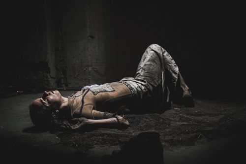 Free A woman lies on a dark floor, evoking themes of despair and pain. Stock Photo
