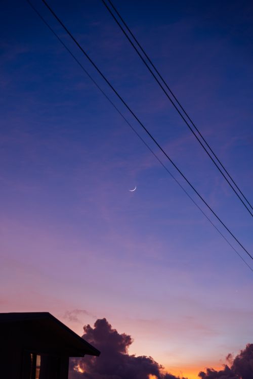 Free Vibrant skyscape with crescent moon, power lines, and colorful twilight hues. Stock Photo