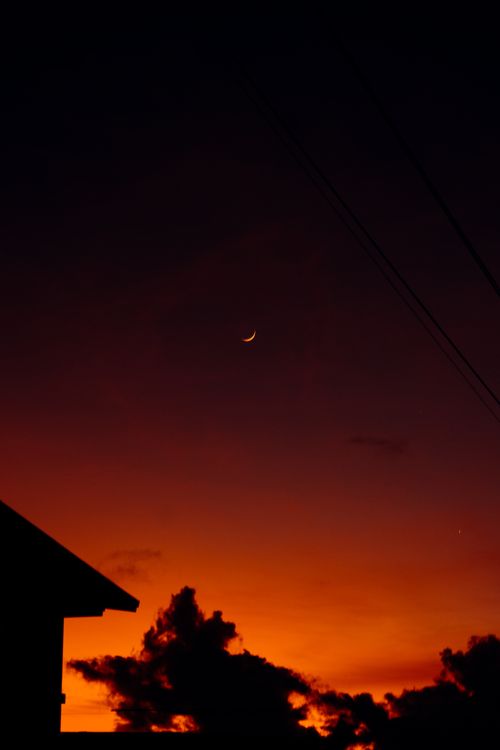 Free A stunning view of a crescent moon with vibrant sunset hues. Stock Photo