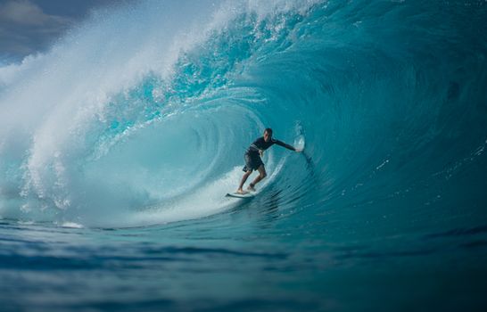A surfer skillfully rides a massive ocean wave, capturing the thrill and essence of water sports.