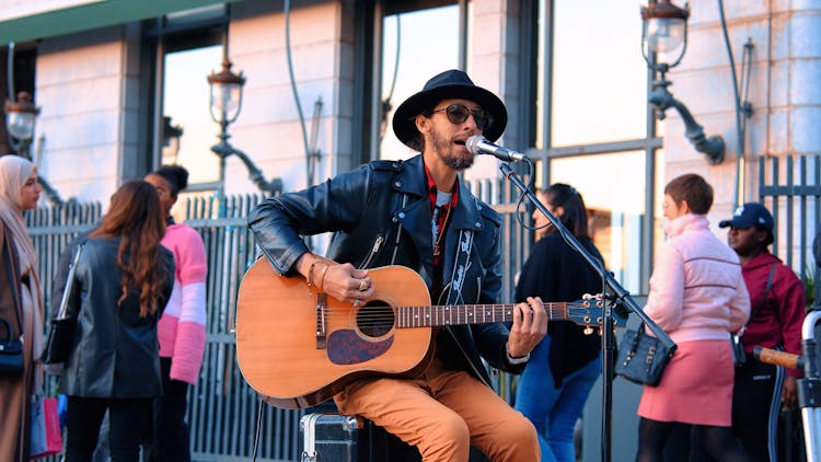 Man Playing Guitar And Singing On Sidewalk